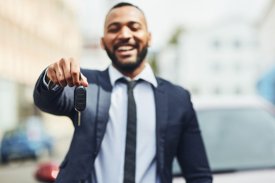 Smiling man in a suit holding his new car keys