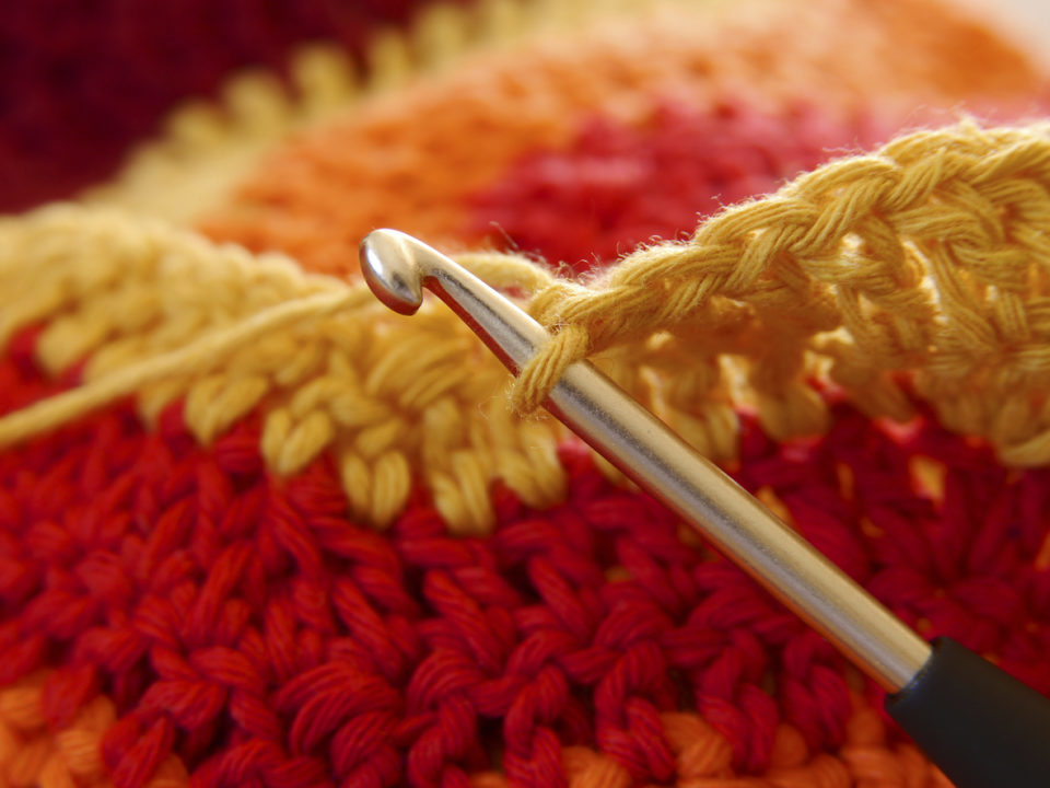 Warm red and yellow crochet blanket and hook