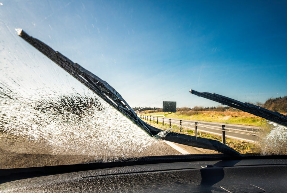Windscreen wipers clearing away washing fluid for better visibility on a journey.